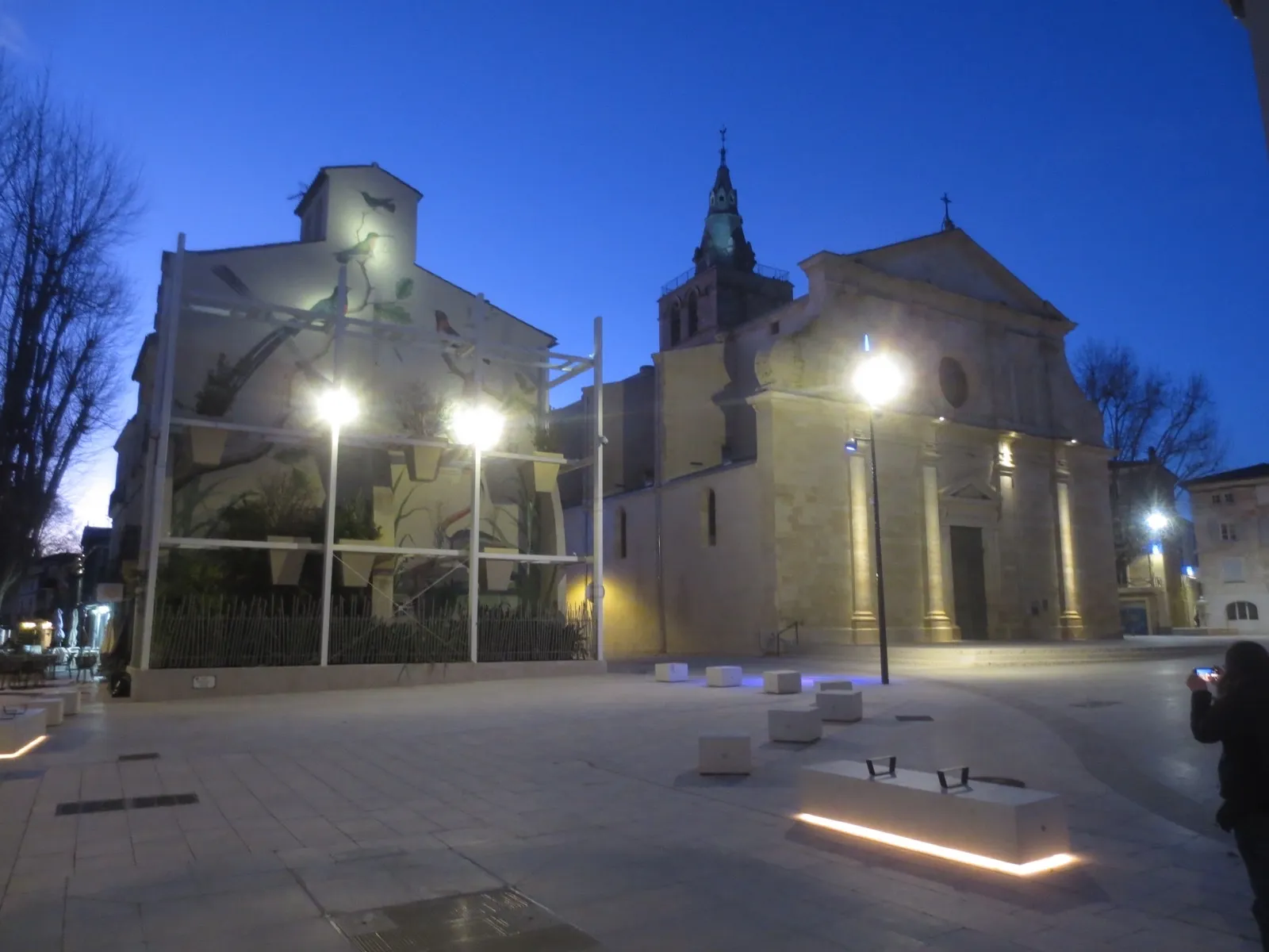 Église et place pavée du centre de Lunel éclairées à la tombée du jour