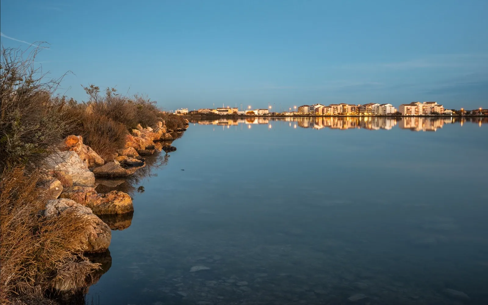 Immeubles de Frontignan-Plage éclairés au crépuscule, reflétés dans l'étang