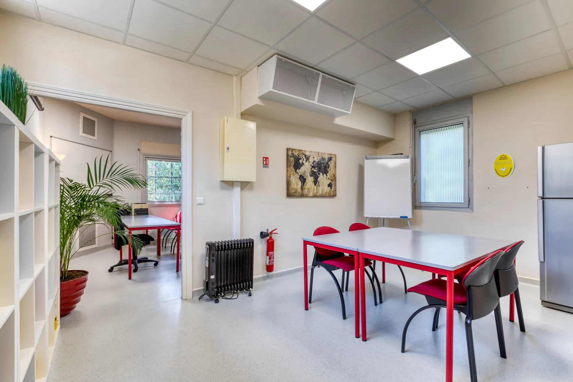 Salle de réunion de l'agence Habitéa : tables et chaises rouges, tableau blanc